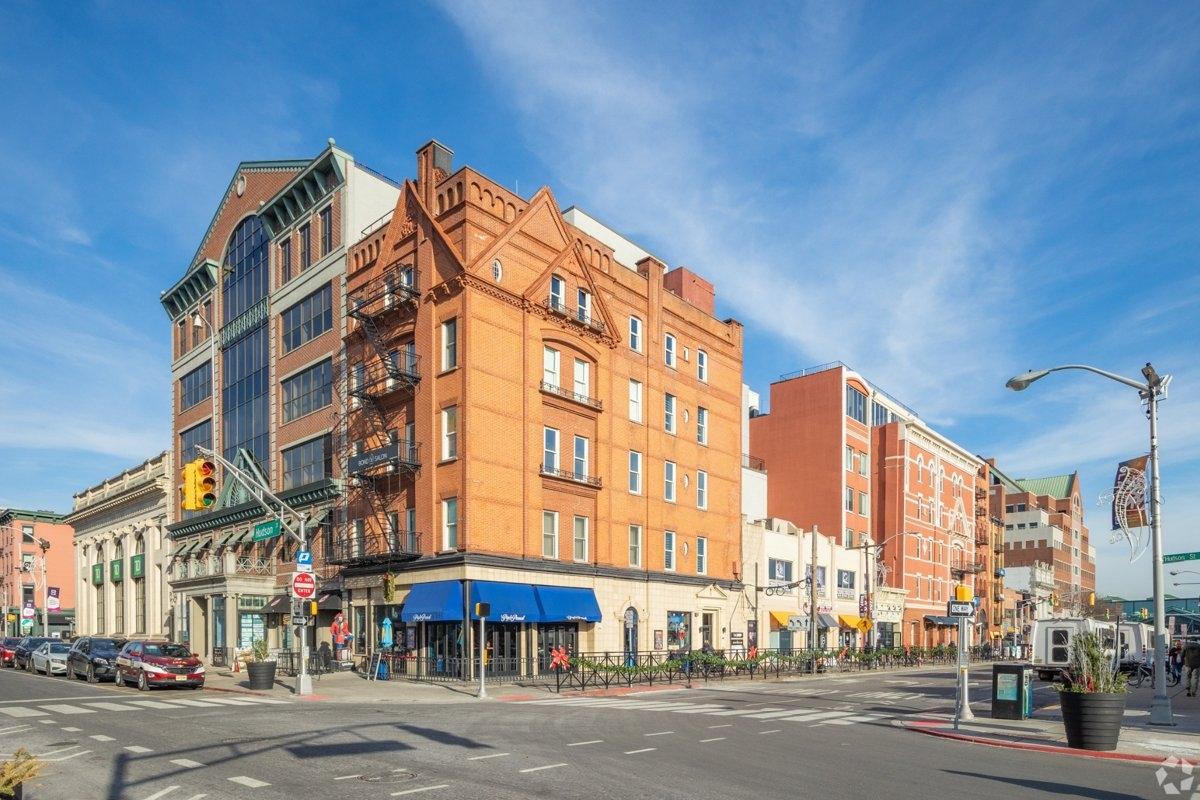 Hoboken street corner with historic buildings, retail shops, and pedestrian activity – vibrant streetscape near Clinton Street Corridor.