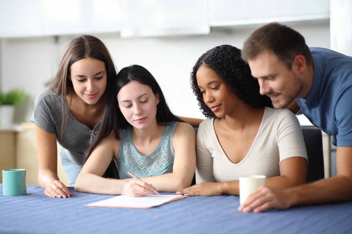 Roommates reviewing paperwork at a table, illustrating the process of fairly splitting rent and utilities in a shared apartment.
