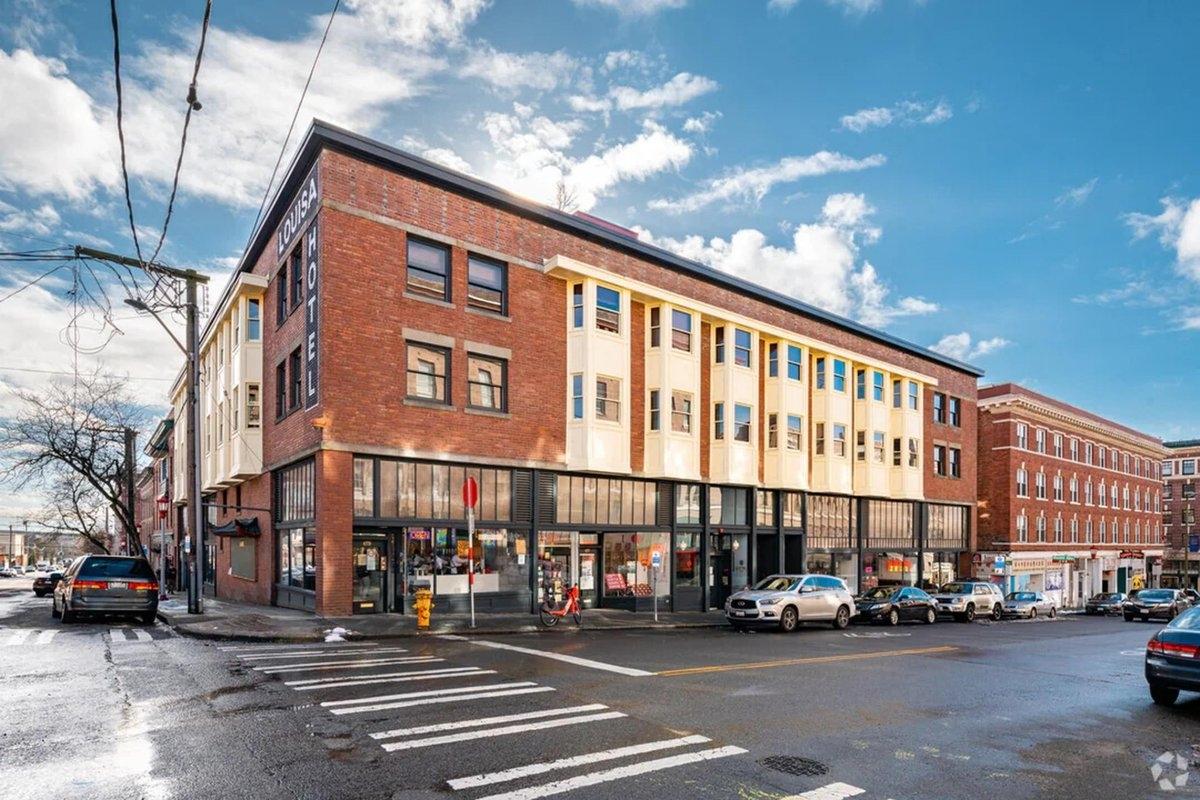 Restored Louisa Hotel in Seattle’s Chinatown-International District, a vintage low-rise apartment complex with street-level shops and cultural heritage appeal.