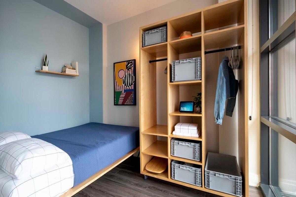 Stylishly converted bedroom in a co-living unit with minimalist design, open storage, and floor-to-ceiling windows — ideal for modern apartment renters.