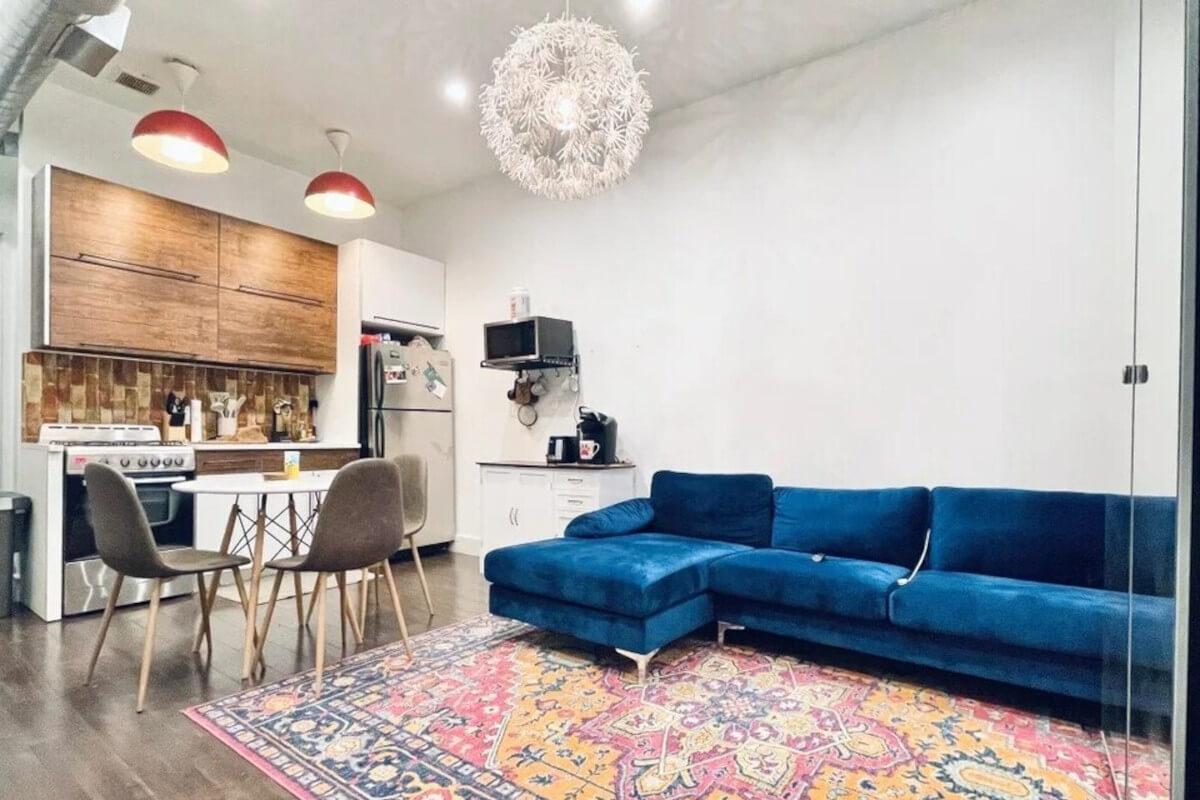 A view of the living room at 1225 Hancock St Unit 2 shows a bright blue couch and quirky lighting.