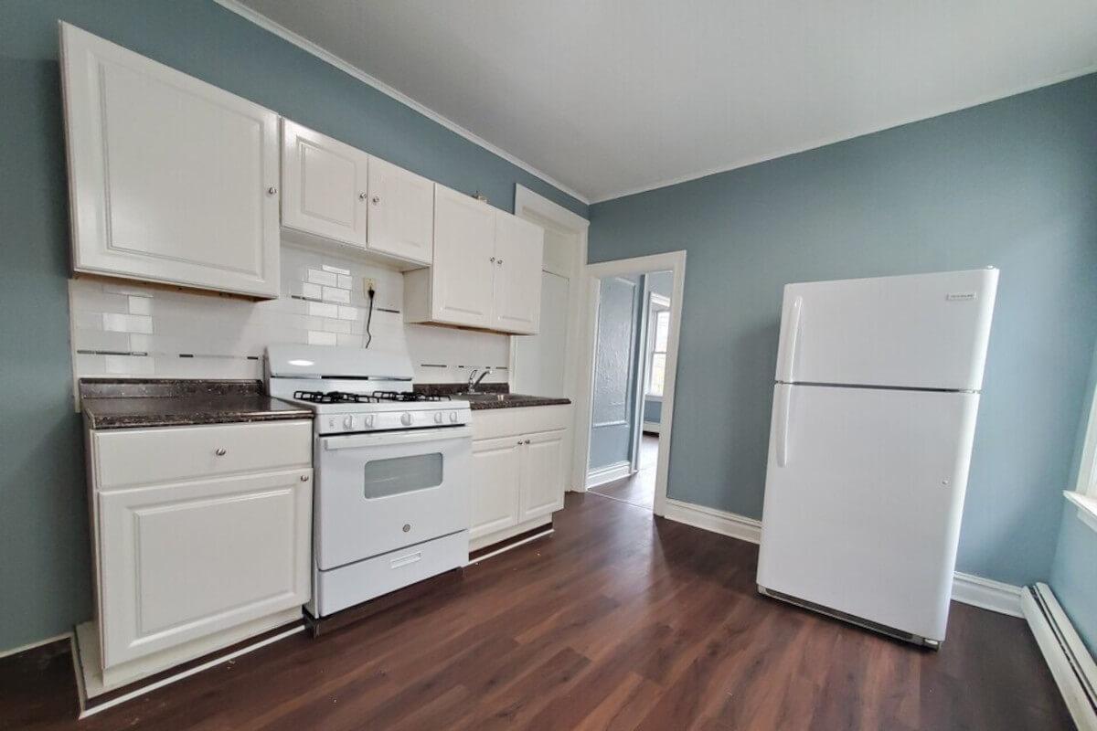 The kitchen at 166 Garfield Ave Unit 2R has blue walls and white tile backsplash.