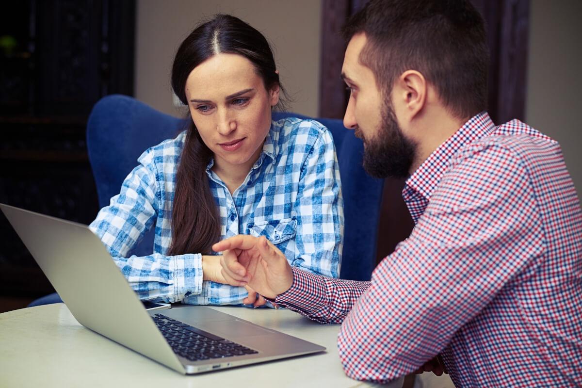A landlord shows a potential tenant something on his computer.