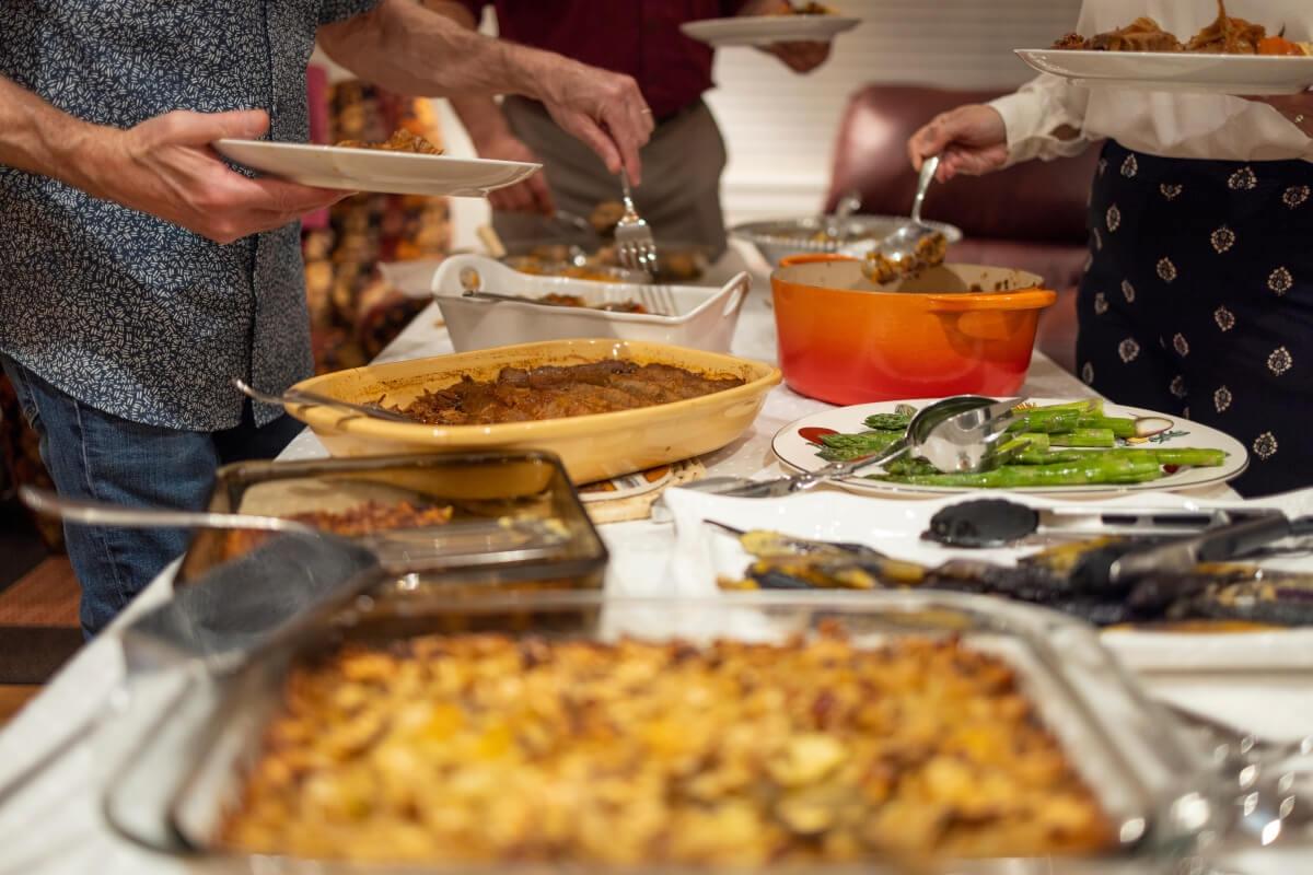 A close-up shot of people serving themselves at a potluck.