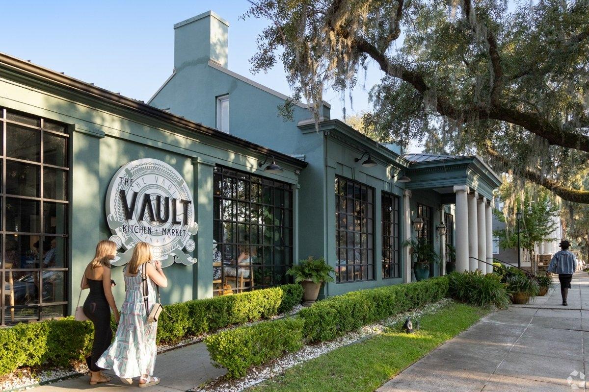 Two women strolling a street in front of an elegant restaurant