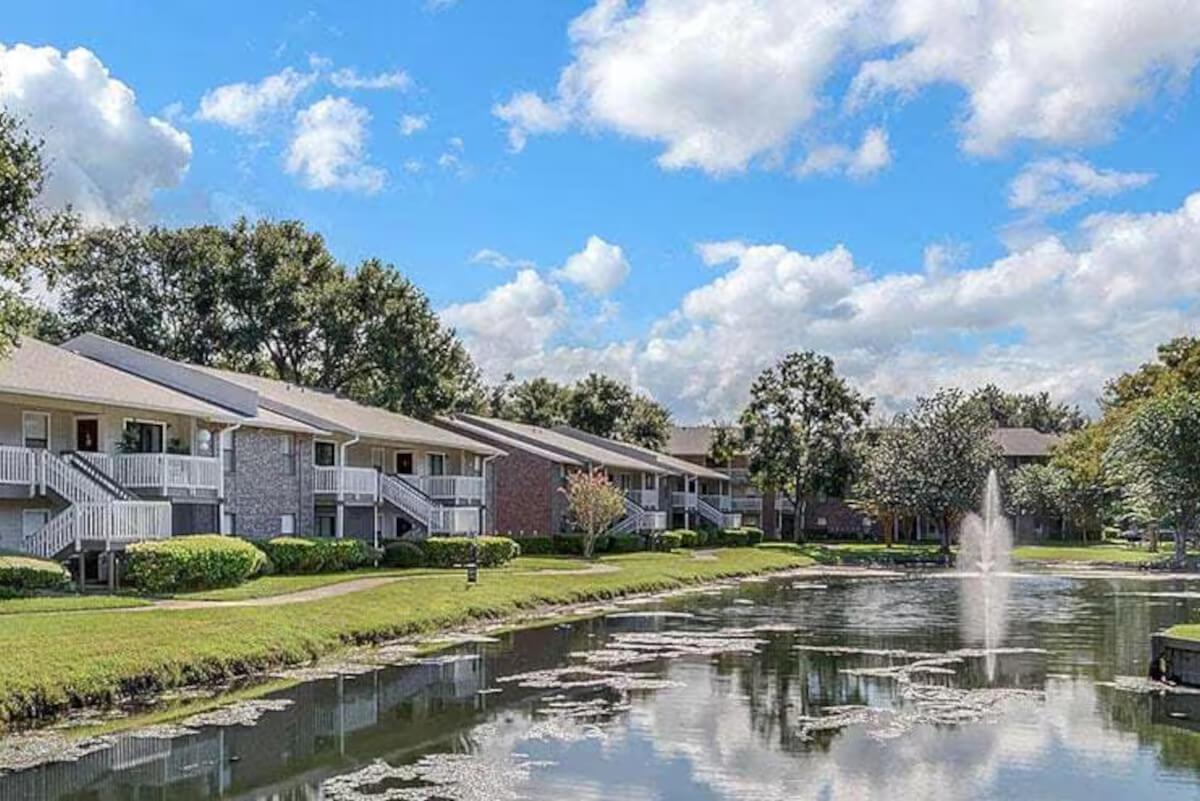 The Cornerstone Apartments buildings along a pond with a fountain.