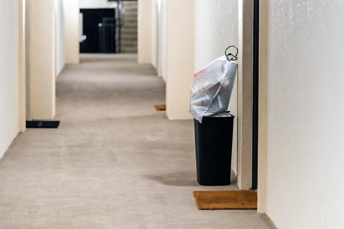 A trash bin outside an apartment door for valet trash service to pick up.