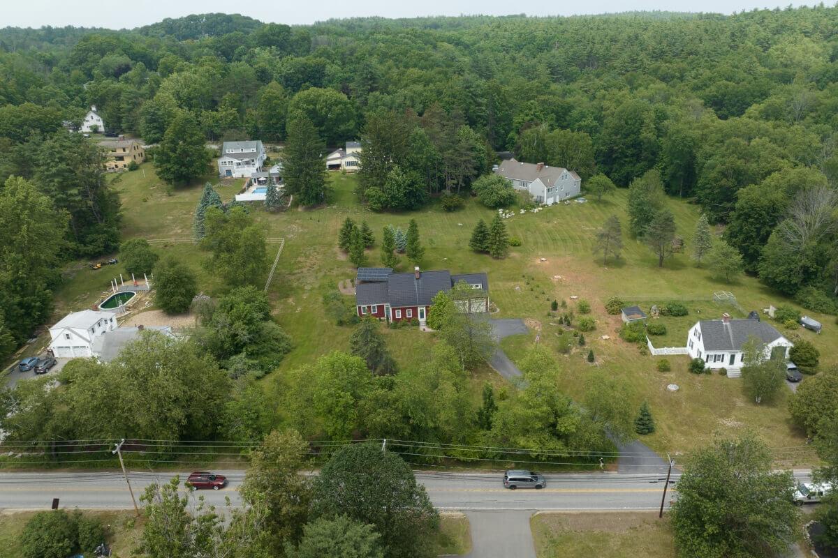 An aerial view of a neighborhood in Bedford shows spread-out homes along a tree-lined street.