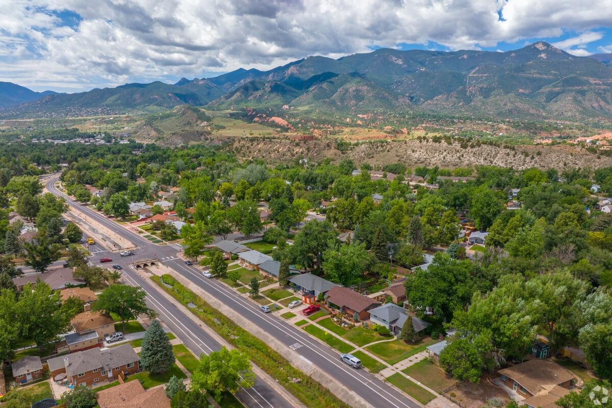 An aerial view of a residential street in Colorado Springs, CO, with mountains in the background.