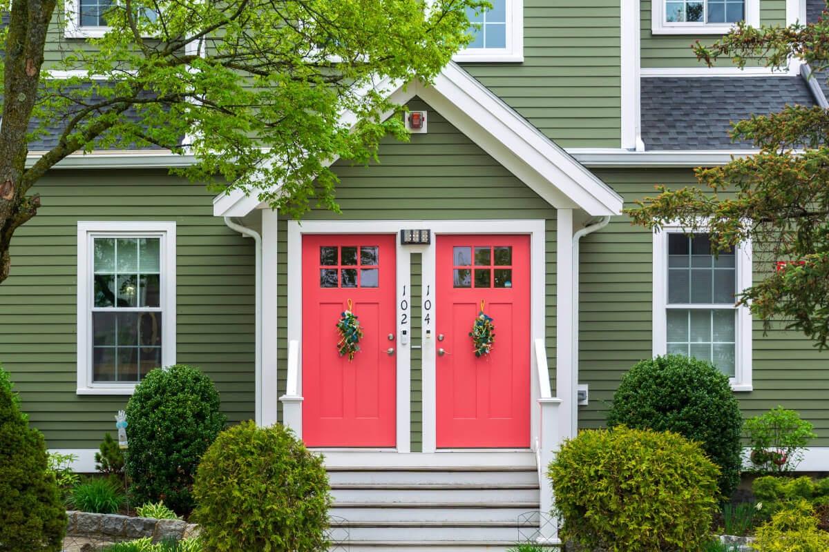 A view of two red doors on a green duplex.