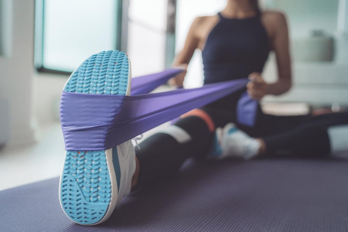 Woman stretches her leg with a resistance band.