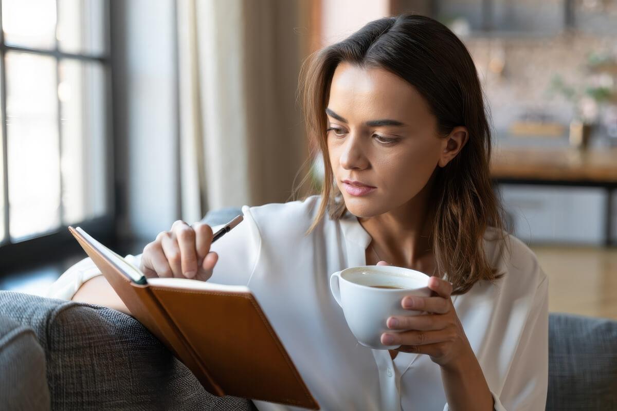 Woman journals with her morning coffee.