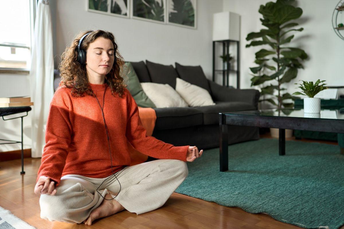 Woman meditates in her living room.