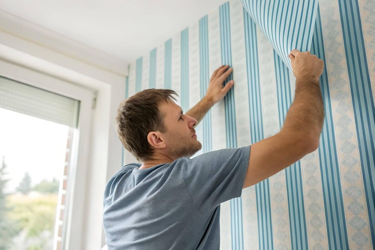 Man puts up temporary wallpaper.