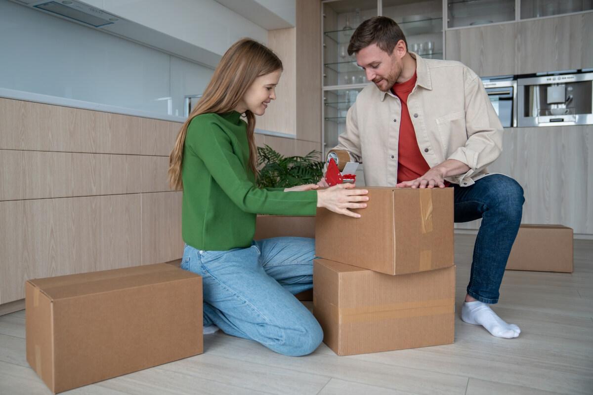 A man and woman packing up the kitchen of their apartment.