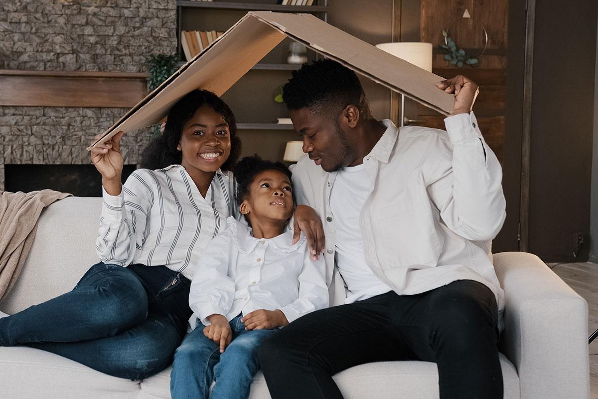 Family sitting under fake house roof.