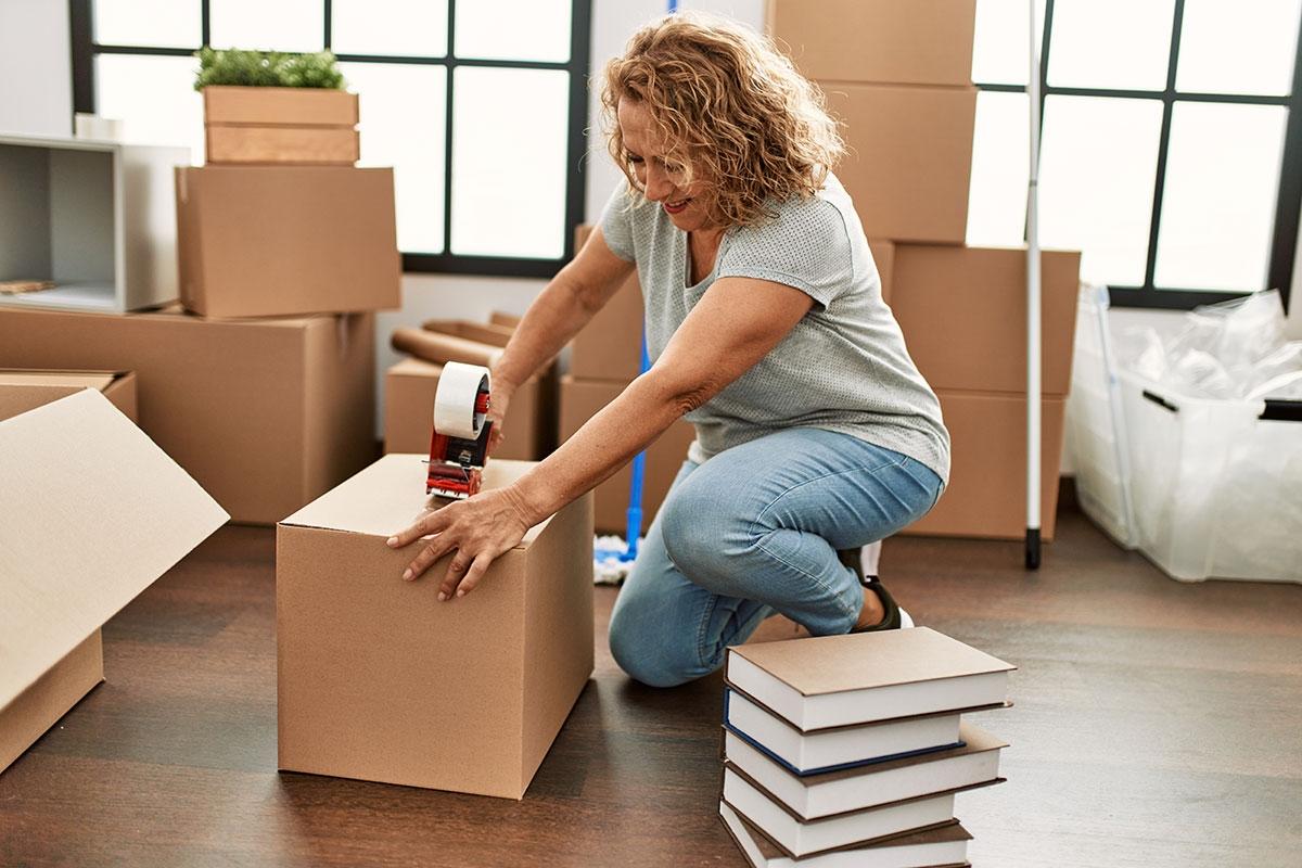 A woman taping up boxes as she prepares to move out of her apartment.