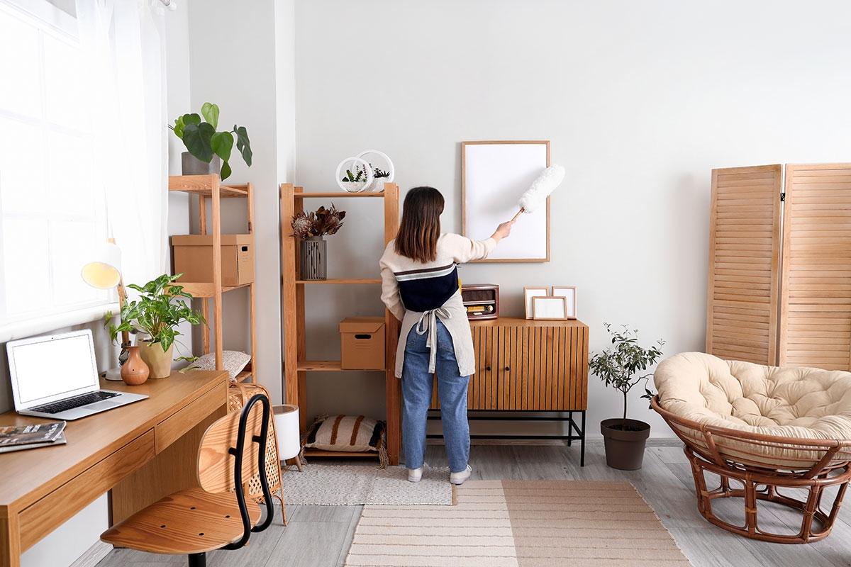 Woman dusting art on the wall.