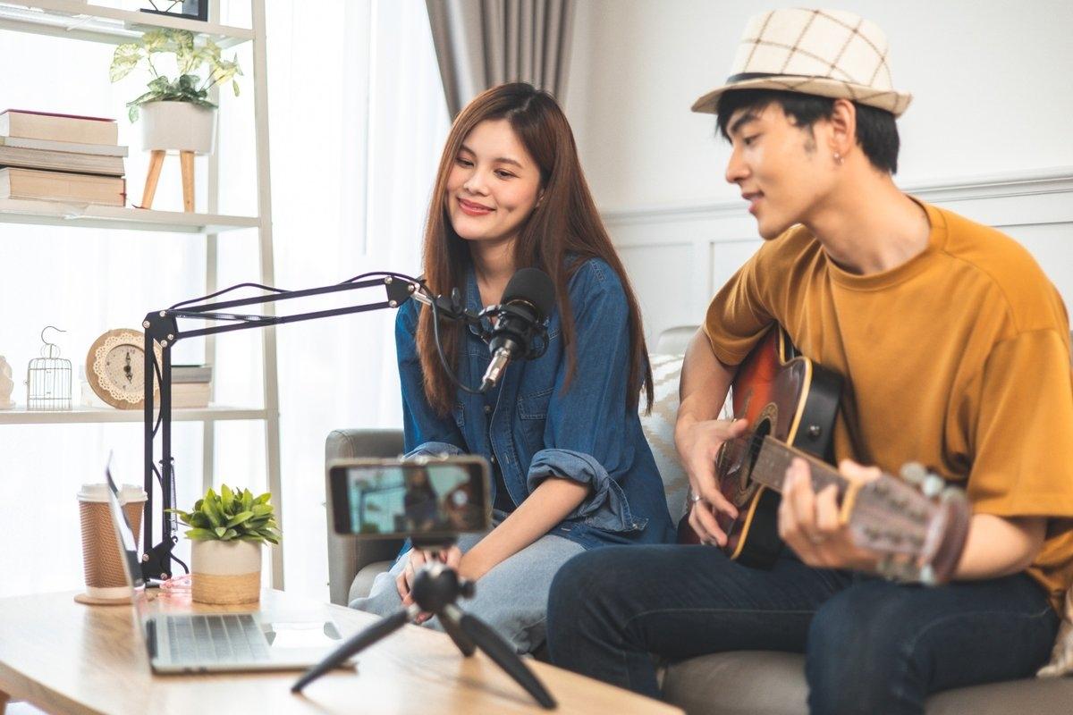 A couple sitting on a sofa playing the guitar on video