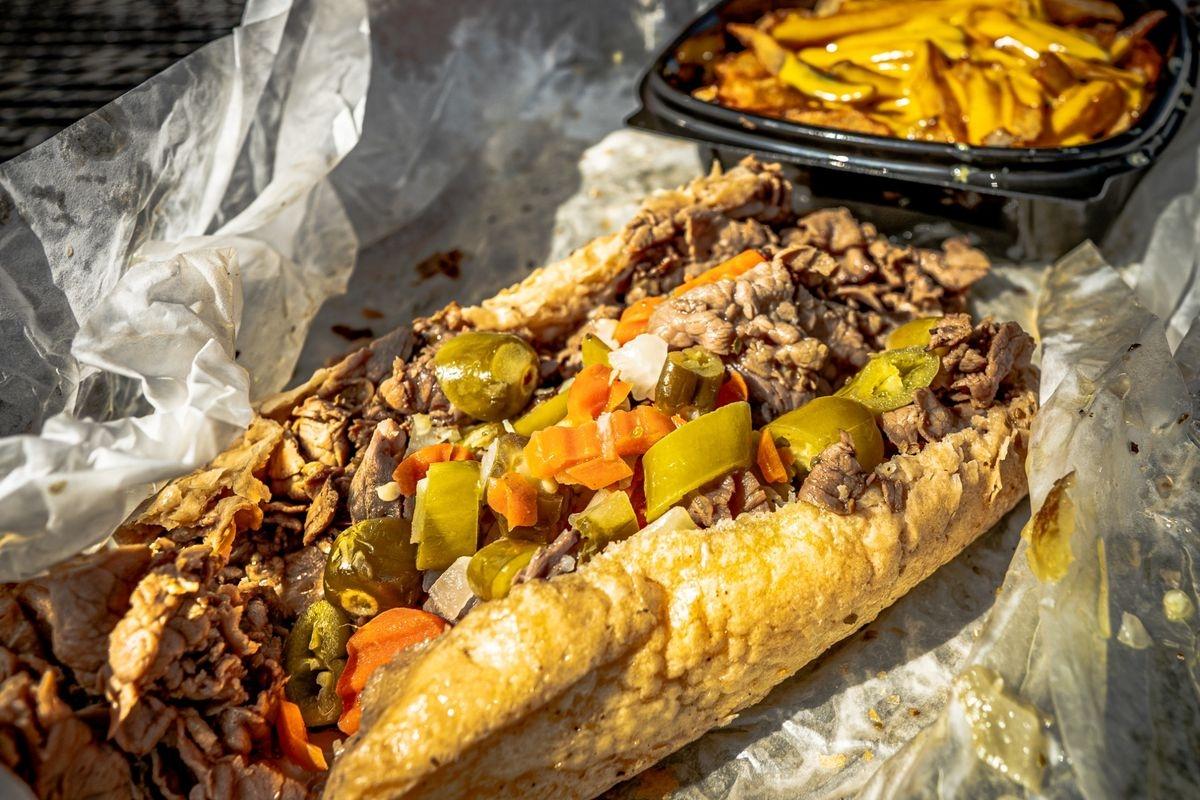 An Italian beef sub sandwich topped with peppers and carrots