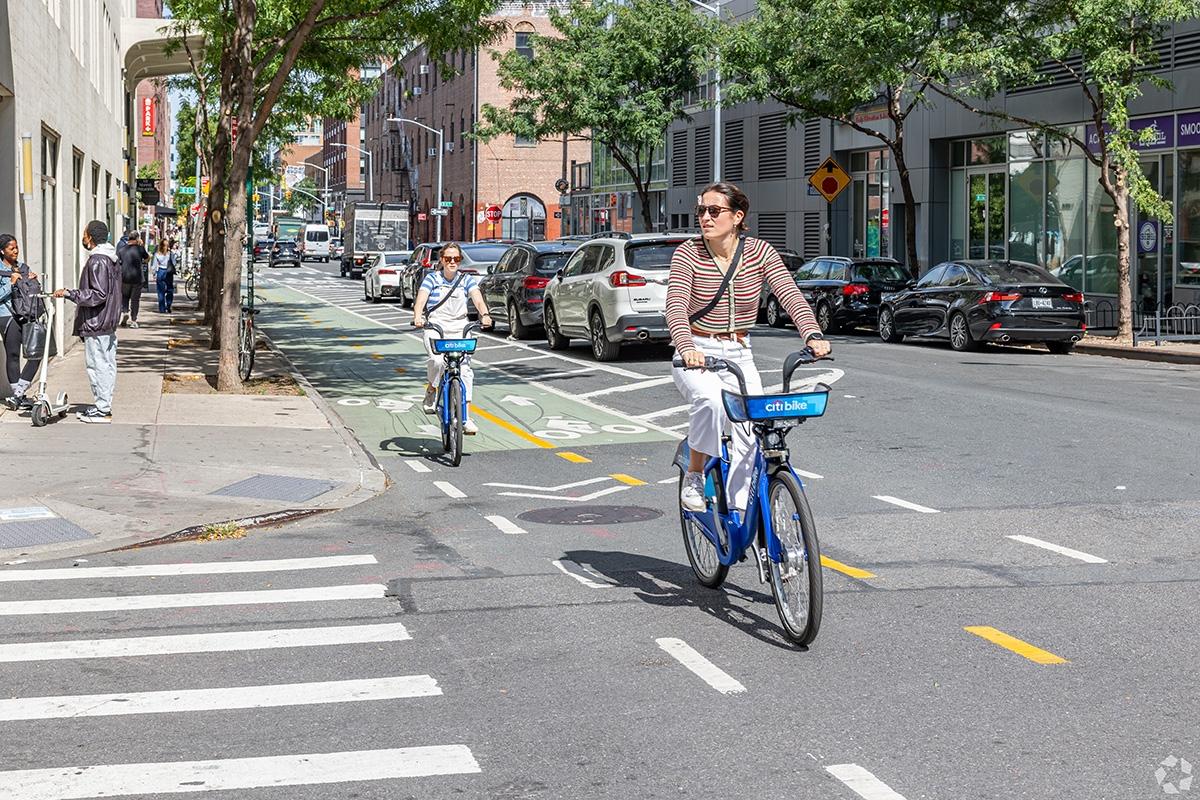 Two women riding Citi Bikes on a road in Williamsburg.