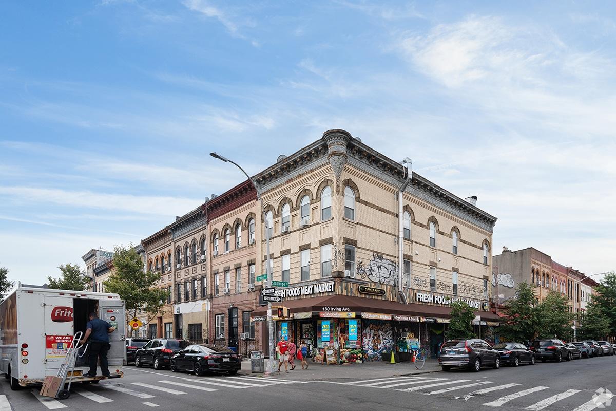 A corner in Bushwick with people visiting a local market.