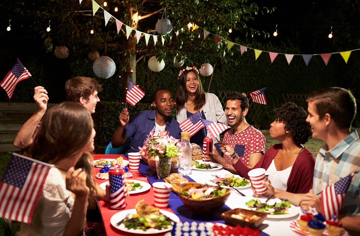 Group of friends surrounded by food at a Fourth of July party.