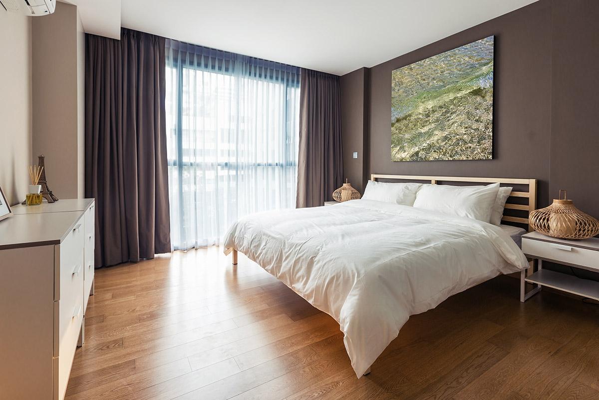 Brown bedroom with a large bed and plenty of open space.