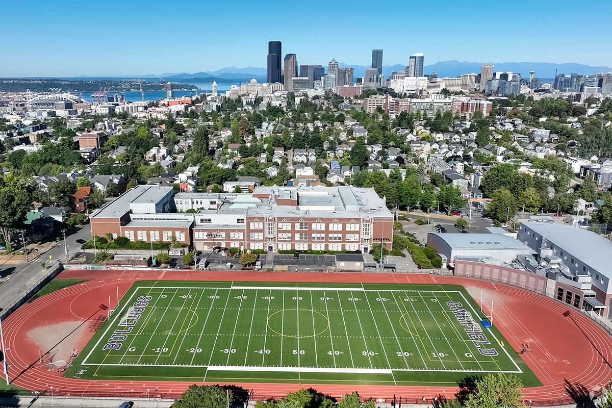 An aerial view of the football field at Garfield High School with the Downtown Seattle skyline in the backdrop.