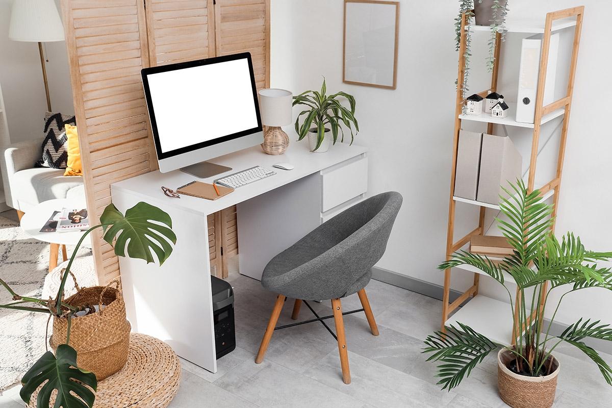 A small desk sits behind a room divider in a studio apartment.