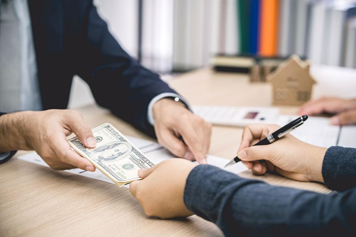 Renter handing landlord money for their security deposit.