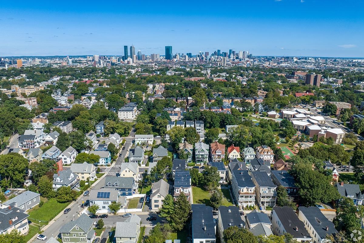 An aerial view of the residential Washington Park neighborhood with the Downtown Boston skyline in the distance.