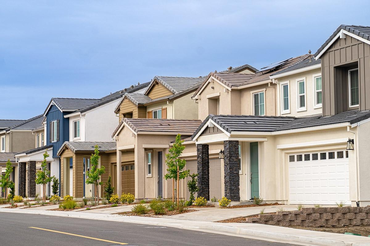 A row of homes sit on a sidewalk.