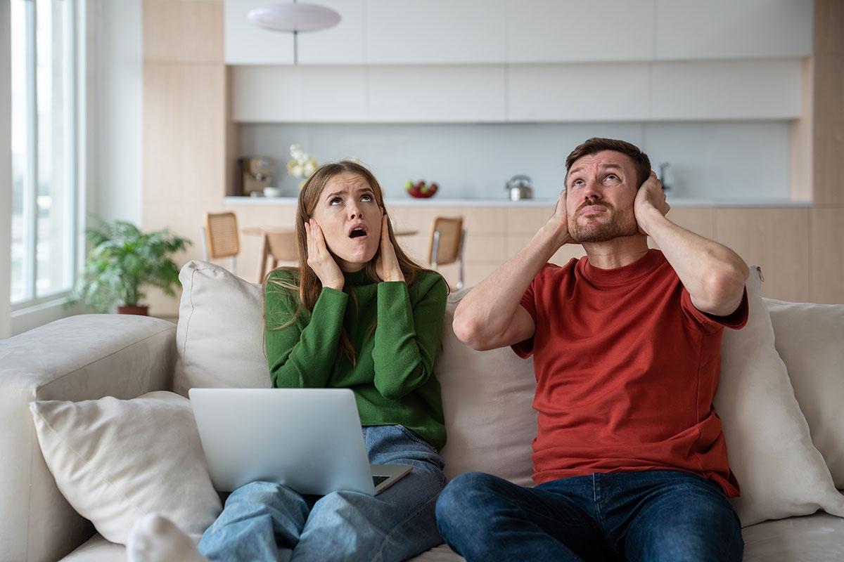 Renters covering their ears because their upstairs neighbor is loud.