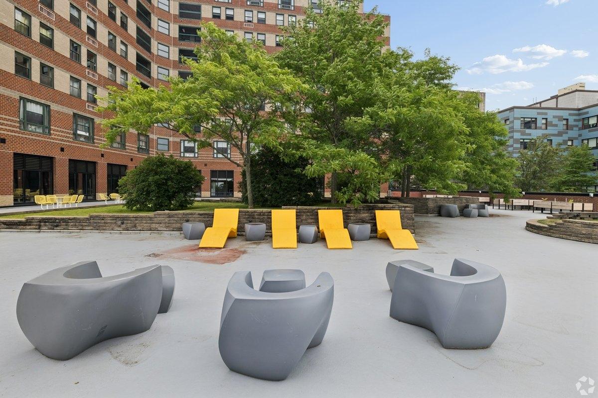 Unqiue chairs sit facing trees in an apartment community courtyard.