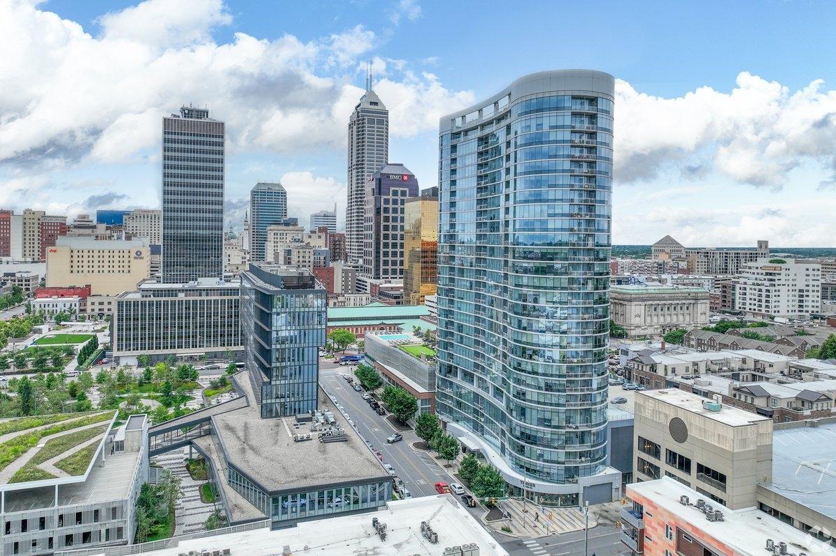 Glass high-rises fill Downtown Indianapolis, with green spaces in between.
