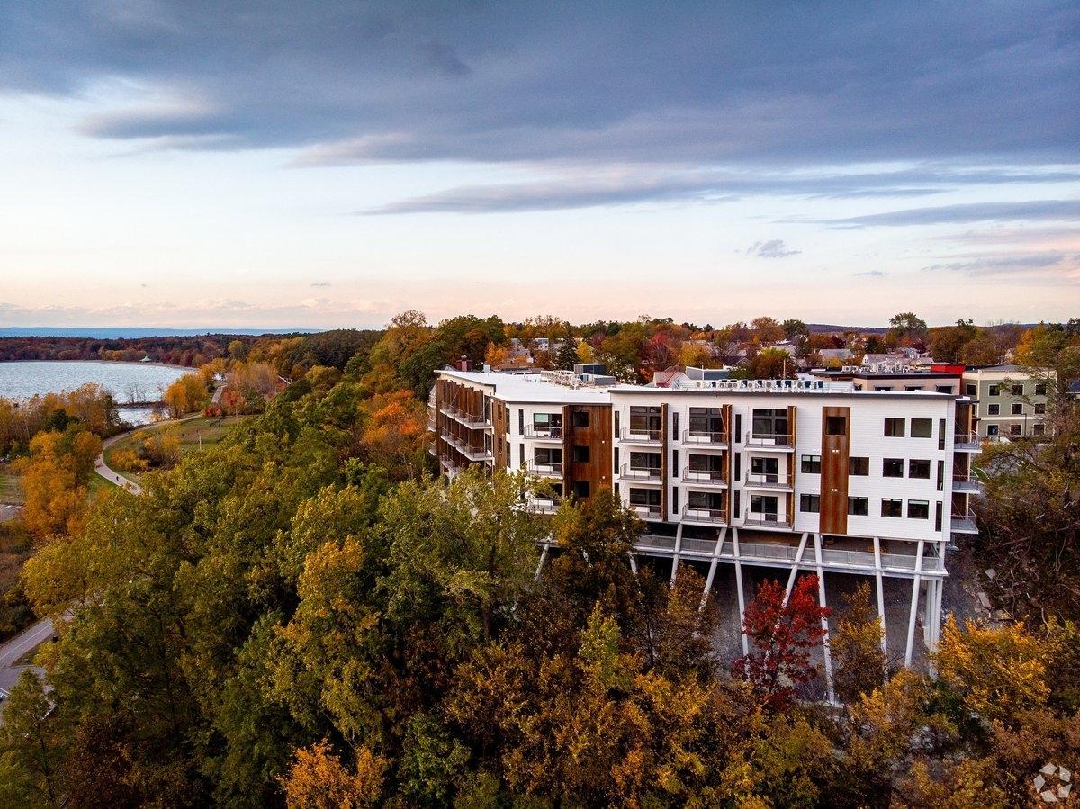An apartment community in Burlington sits on a cliff's edge with the trees turning fall colors underneath it.