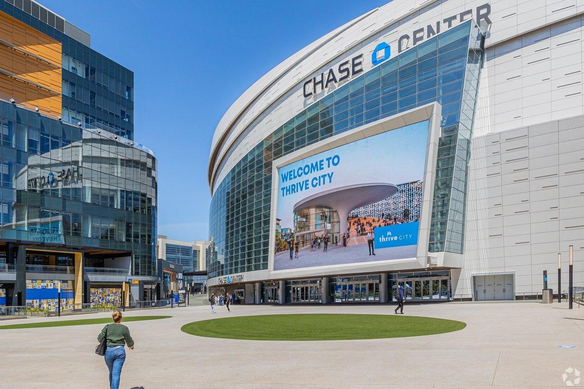 People walk around the front entrance of Chase Center.