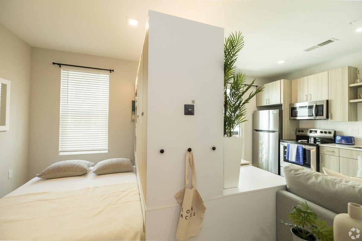 A studio contains transforming furniture that has been moved to reveal a bed.
