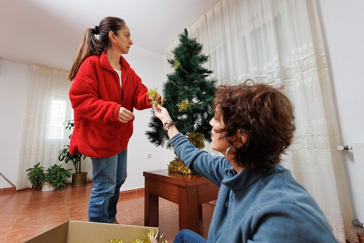Renters decorating a Christmas tree in their apartment.
