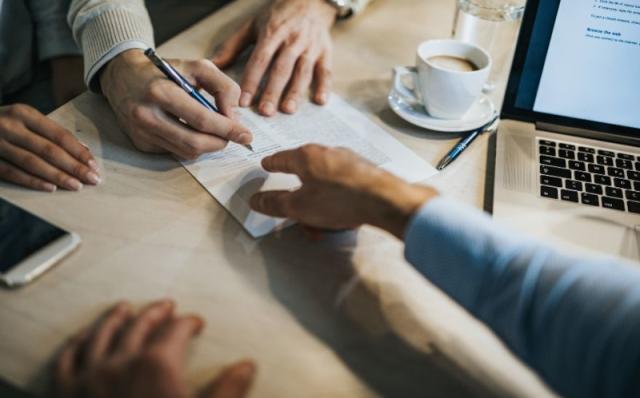 Person pointing to where to sign on lease agreement form.