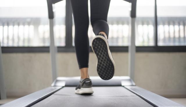 Person walking on a treadmill facing a window.