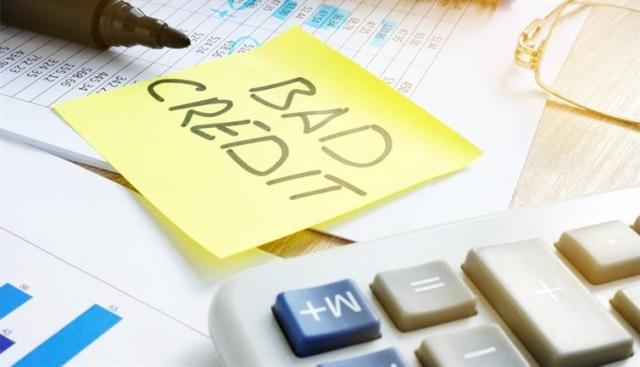 A post-it note with "bad credit" written on it next to a calculator.