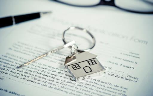 A house-shaped charm and a key over a leasing agreement