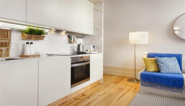 A small sleek kitchenette bordering a living room