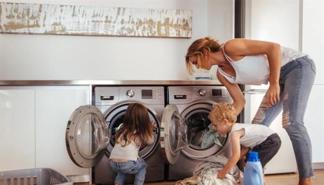A woman and two children loading a washer and dryer