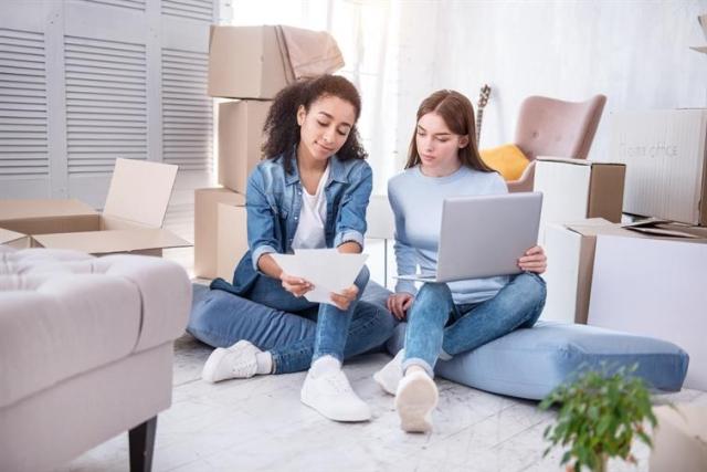 Roommates sitting on the floor reviewing bills.