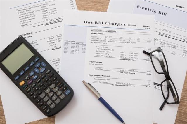 A stack of bills beside a calculator and pen