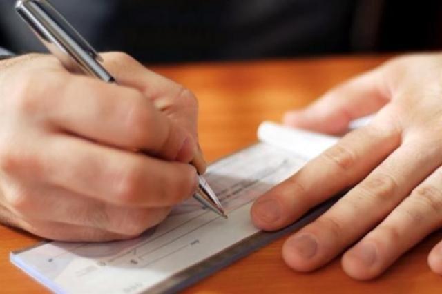A person fills out a check for their landlord.
