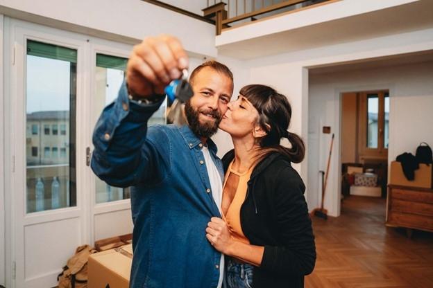 A couple embraces while showing off the keys inside their new apartment.